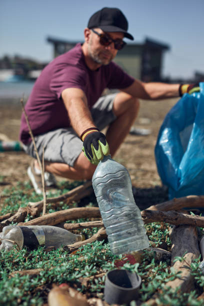 istock Environmental activist cleaning river shore from piled up trash. 2186998043