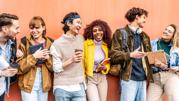 istock Joyful large group generation z multiracial students looking smiling each other leaning against wall - Young international university people together standing holding backpacks and workbooks outdoor 2187005753