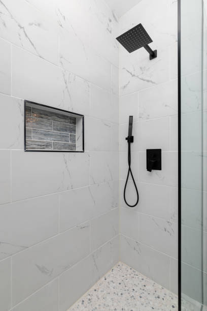 istock A white tiled shower with a black faucet. 2187007821