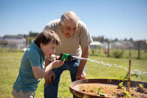 istock Grandfather and grandson watering vegetable patch 2187013236