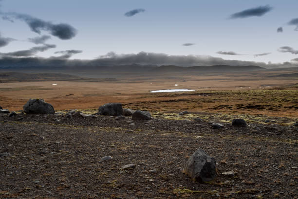 Fields, pastures and meadows. Mountains in the background. Autumn cloudy sky. Area of Thingvellir National Park, south-west Iceland.