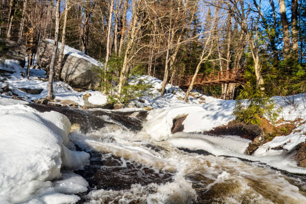 Stubbs Falls with ice and snow in Arrowhead Provincial Park in winter. An unrecognizable person is on the bridge