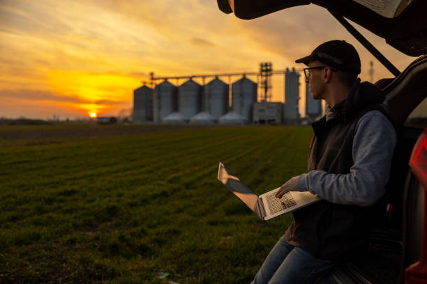 Caucasian Farmer Working on Laptop in Field at Sunset