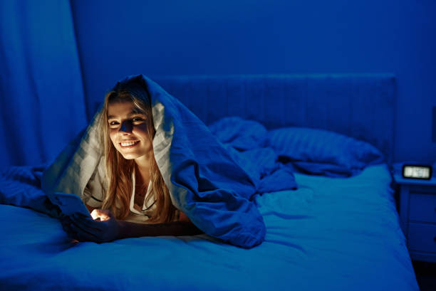 istock A young woman is using her smartphone while comfortably nestled under a blanket at night 2187022890