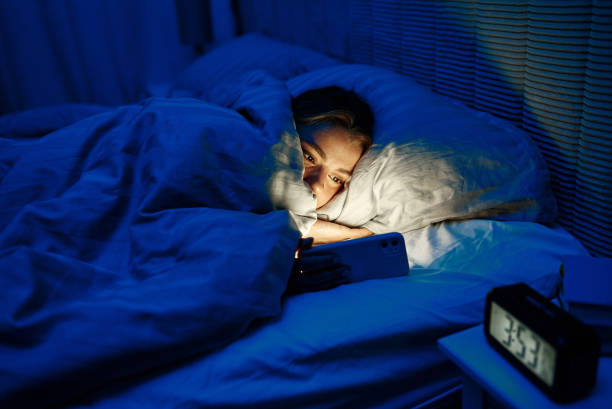 istock Engaging in Late Night Smartphone Use Snuggling under a cozy blanket with blue light from device 2187022935