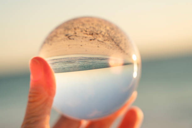 Hand holding a crystal ball, mirroring sea, sky and sandy beach, Madagascar