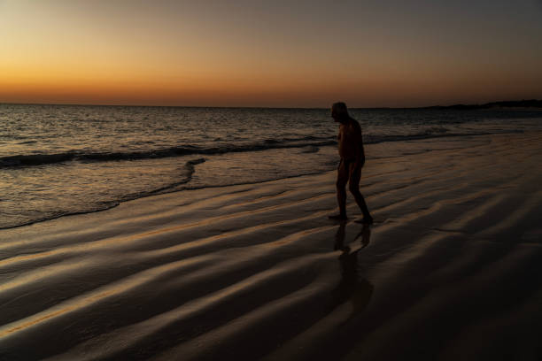 Rear view of a person standing by the sea at sunset. Long exposure photo