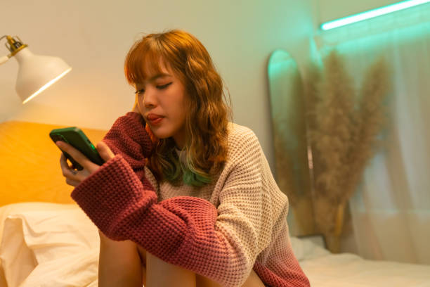 istock Depressed Asian woman using mobile phone in bedroom. 2187031091