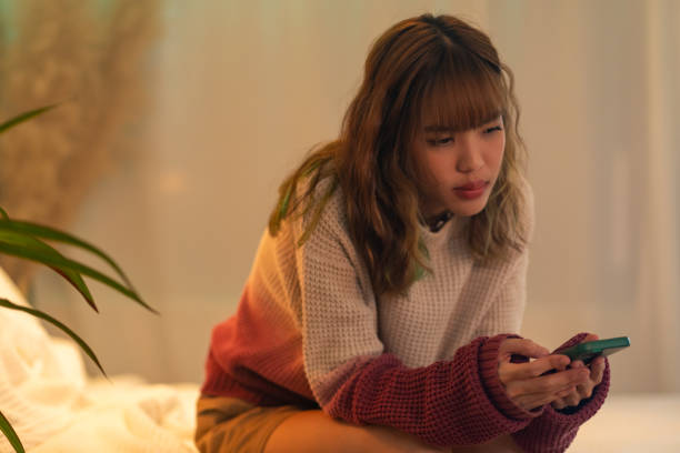 istock Depressed Asian woman using mobile phone in bedroom. 2187031201