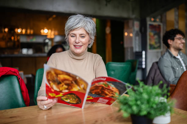 istock Smiling woman holding menu in vibrant cafe environment. 2187042952