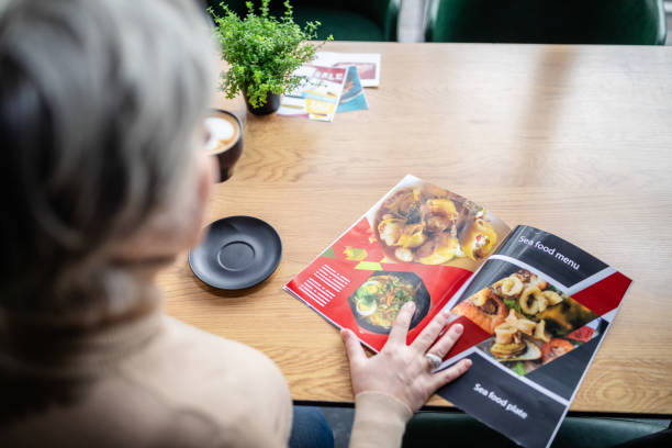 istock Woman reading menu at cozy cafe table with coffee cup. 2187043340