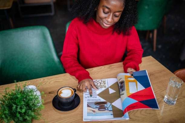 istock Young woman reading magazine while sipping coffee. 2187043678