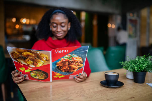 istock A woman in a red sweater reads a restaurant menu. 2187045177