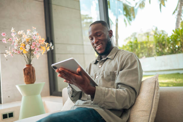 istock Cheerful Man with Tablet Lounging at Home 2187047331