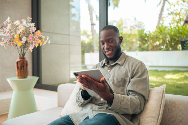 istock Cheerful Man Engaged with Tablet on Living Room Couch 2187047336