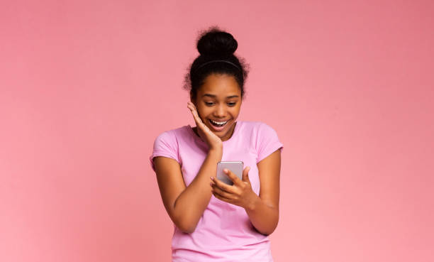 istock Unexpected Message. Girl Looking At Smartphone Over Pink Studio Background 2187051598