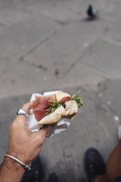 istock Hand Holding an Italian Panino with Prosciutto and Arugula 2187065624