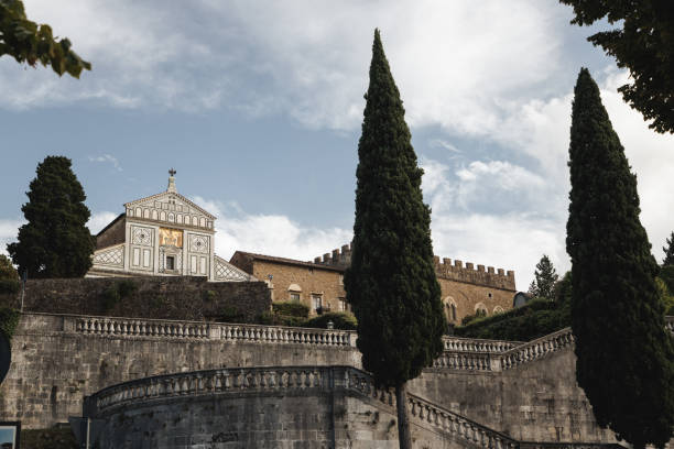This serene shot captures the striking facade of the Church of Santa Maria Novella in Florence, framed by the surrounding greenery. The church’s intricate geometric design and iconic mosaic are visible above the tree line, offering a glimpse into the rich artistic heritage of the city. The early evening light gently illuminates the church, creating a perfect balance between nature and architecture.