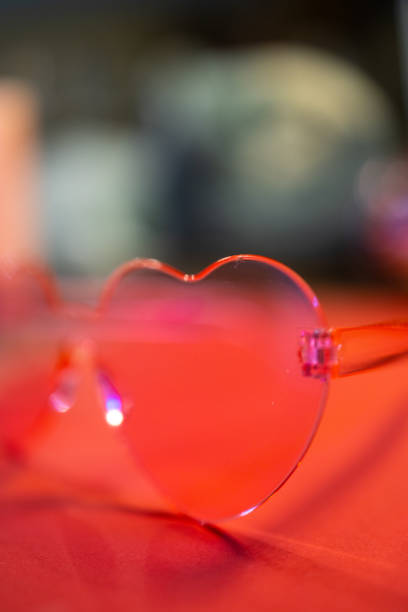 istock Closeup of heart-shaped pink glasses on a red surface 2187066337