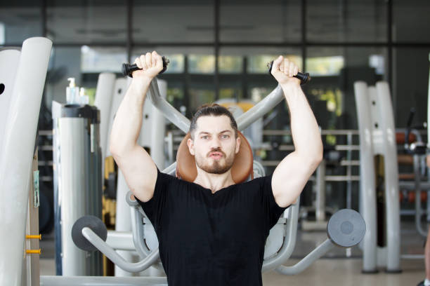 istock Hispanic man doing a weight training exercise in the gym. 2187066702