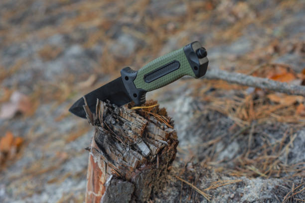 istock Tactical knife with a green handle in the forest. Tool against the natural leather. 2187069317