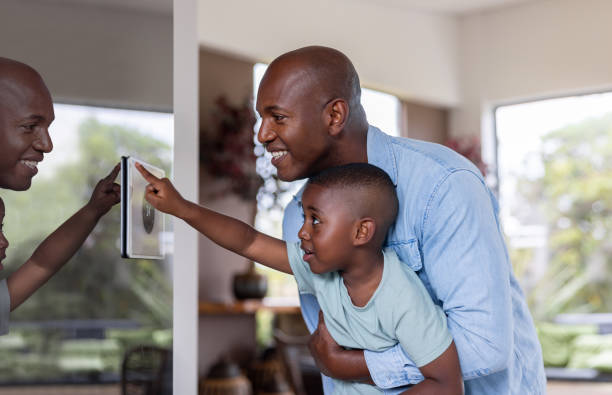 istock Father lifting his son to allow him to control the temperature at home from a tablet 2187069455