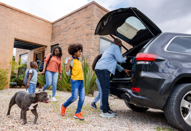 istock Happy family going on a road trip and loading things into the car 2187069458