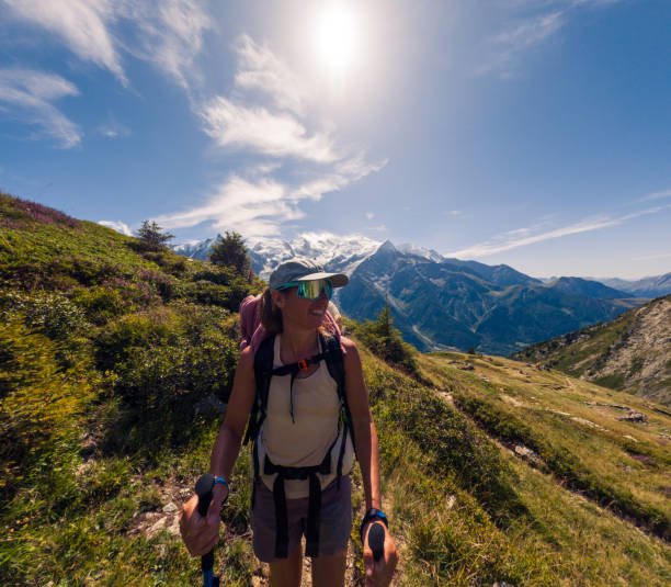 Individual trekking through scenic mountain landscape with peaks in the background. Adventurer walking on narrow path surrounded by nature. Outdoor activity in summer mountains.