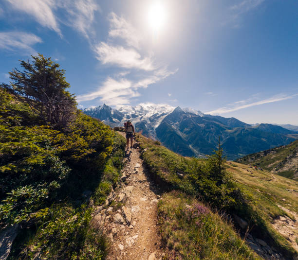 istock Hiker walking along mountain trail with trekking poles under sunny sky 2187071401