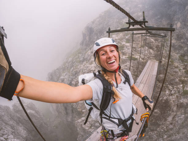 Woman Taking Selfie While Crossing Suspension Bridge in Mountains