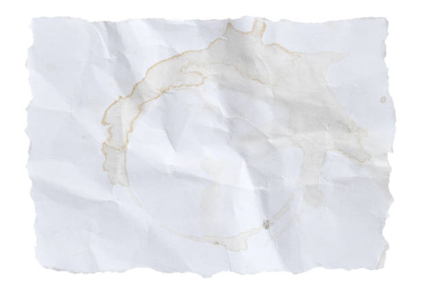 Blank empty plain old white colored, stained, messy dirty ruined, run down, damaged textured crumpled paper sheet with copy space and torn uneven edges over horizontal  background with beige brown tea cup stains blot. There is blotted distorted circular wet tea cup stains making it messy, damaged and dirty.