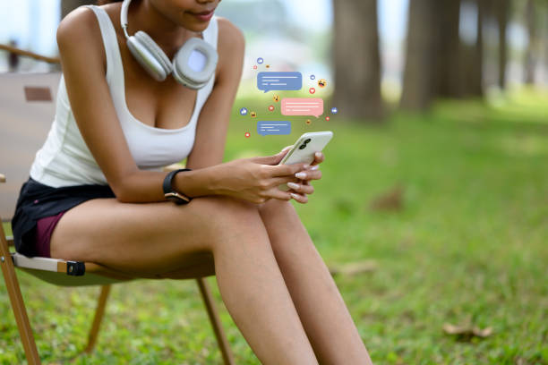 istock Young woman scrolling through mobile phone with social media notifications while relaxing after her workout 2187081029