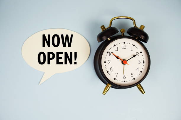 istock Now Open text on speech bluble with magnifying glass top view on blue background 2187082111
