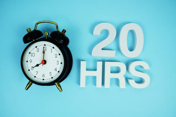 istock 20 Hrs alphabet letters and alarm clock top view on blue background 2187083677