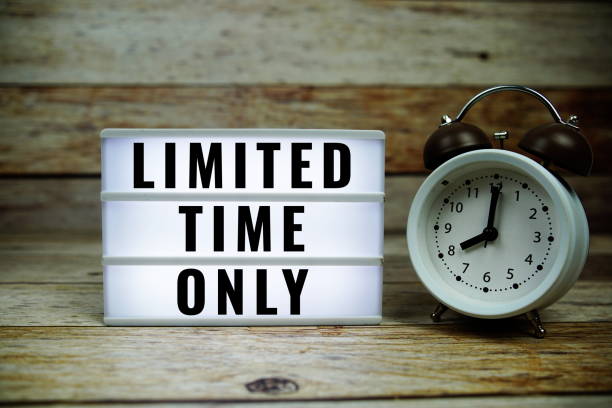 istock Limited Time Only text on LED lightbox with alarm clock on wooden background 2187083773