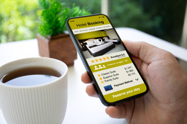 istock Man hand hold phone with hotel booking application background cafe 2187083814