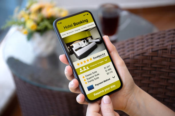 istock Man hand hold phone with hotel booking application background cafe 2187084002
