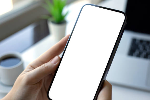 istock male hand holding phone isolated screen background table with laptop 2187084398