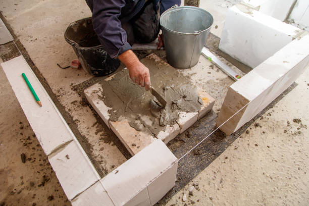 istock A man is laying down and using a trowel to spread cement on a wall 2187084411