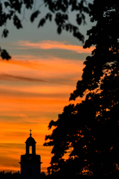 Silhouette of church and tree against dramatic sky