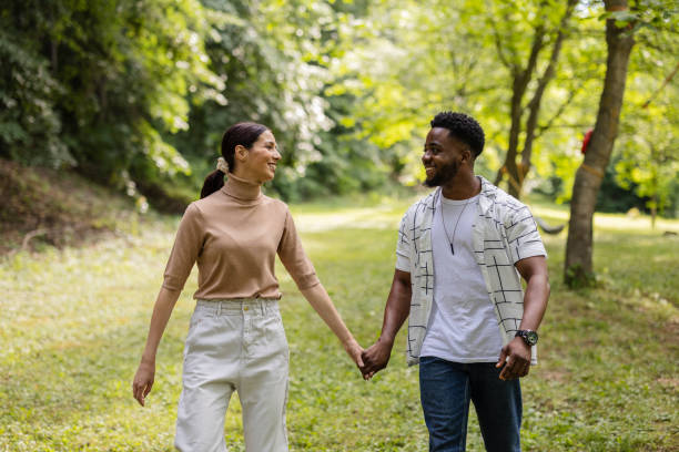 istock Happy multiracial couple holding hands and walking in park 2187086310