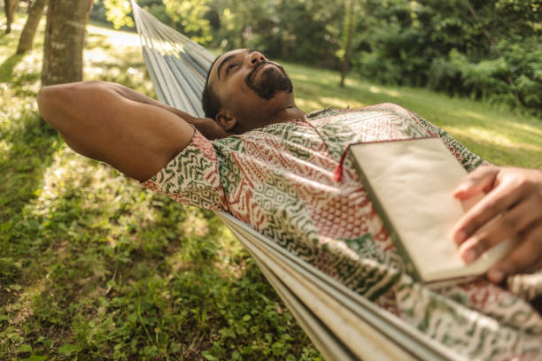 istock Serene man relaxing in hammock with book, embracing tranquility in nature 2187087112