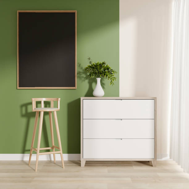 istock A minimalist room features a simple drawer, a stool, a picture frame, and a white and green wall. 2187089074