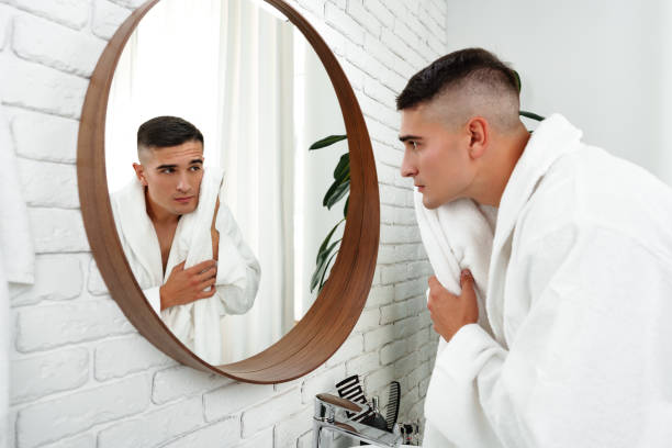 istock Young man looking in the mirror in the bathroom 2187091184