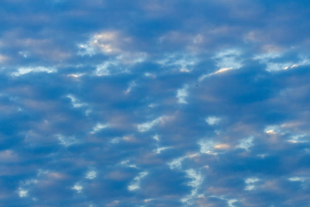 beautiful blue skies with puffy white and colored clouds at sunrise