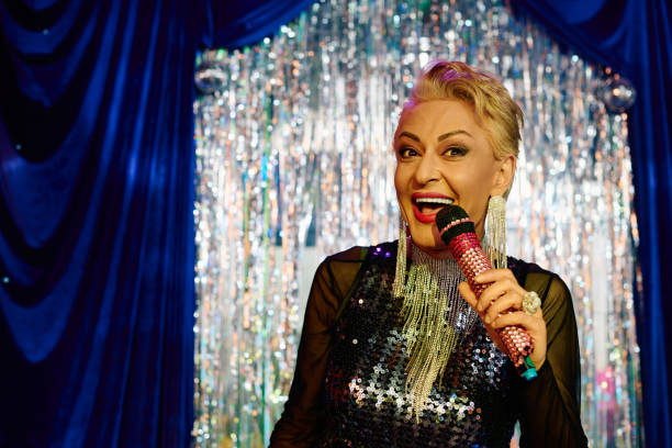 A captivating drag queen shines on stage, showcasing extravagant makeup while performing.