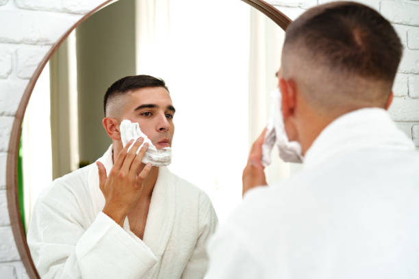 istock Reflection of a young man shaving in bathroom mirror close up 2187100942