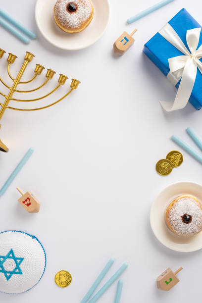 istock Festive Hanukkah vertical setting featuring a menorah, donuts, dreidels, blue candles, and a wrapped gift. Perfect for celebrating Jewish traditions and family gatherings 2187102049