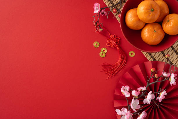 istock Festive Chinese New Year scene featuring oranges, red decorations, and cherry blossoms on a vibrant red background, symbolizing prosperity and joy 2187102080