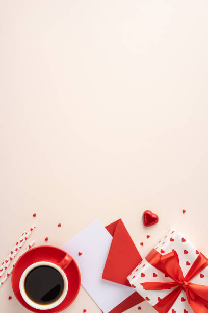 istock Romantic Valentine's day vertical setting with a cup of coffee, red envelopes, gift box, and heart accents on a cream surface 2187102141